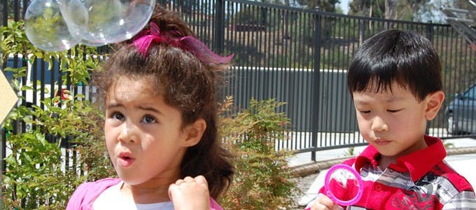 Child looking up at bubbles, child holding a bubble wand