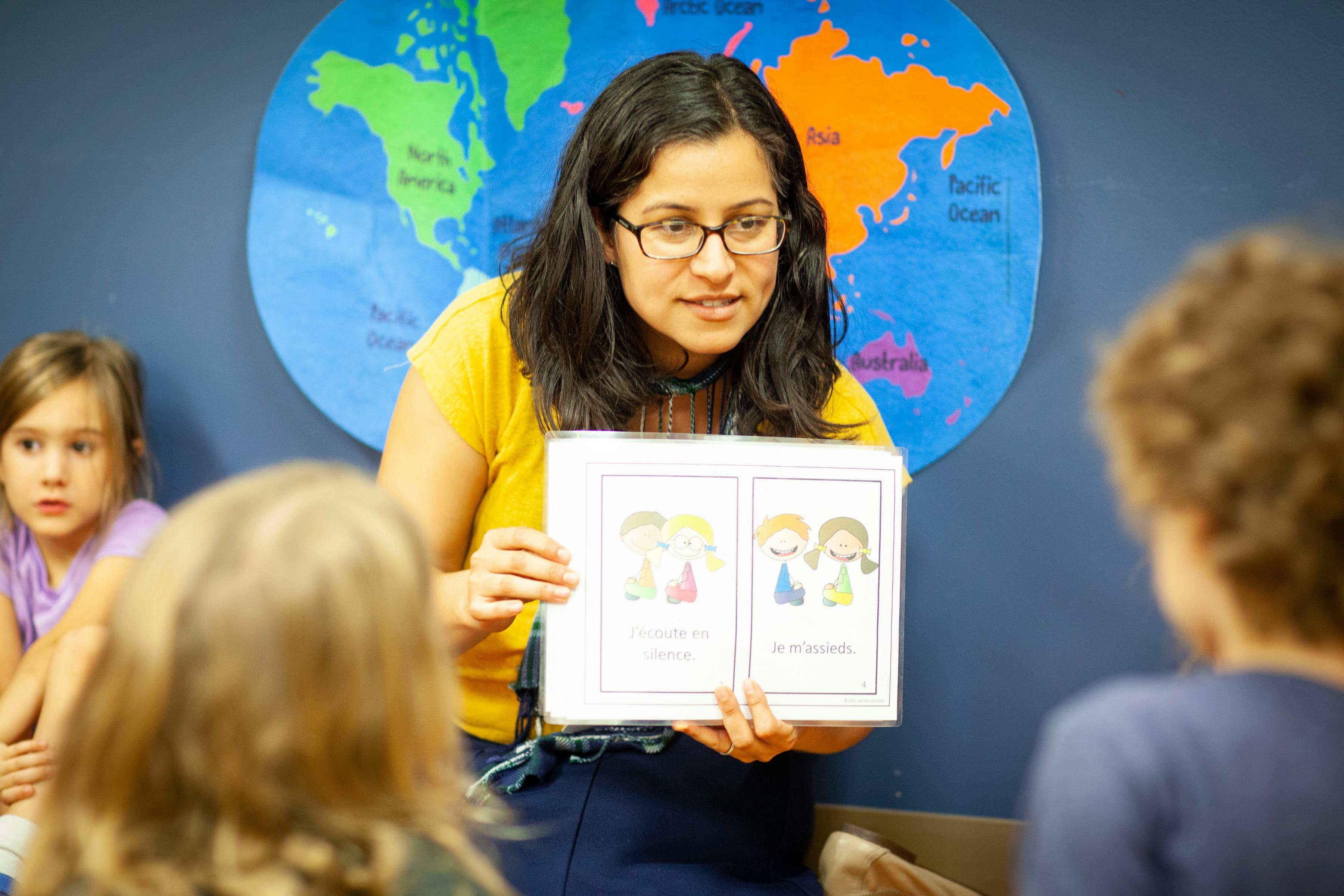 Person holding up a book with illustrations to children in a classroom