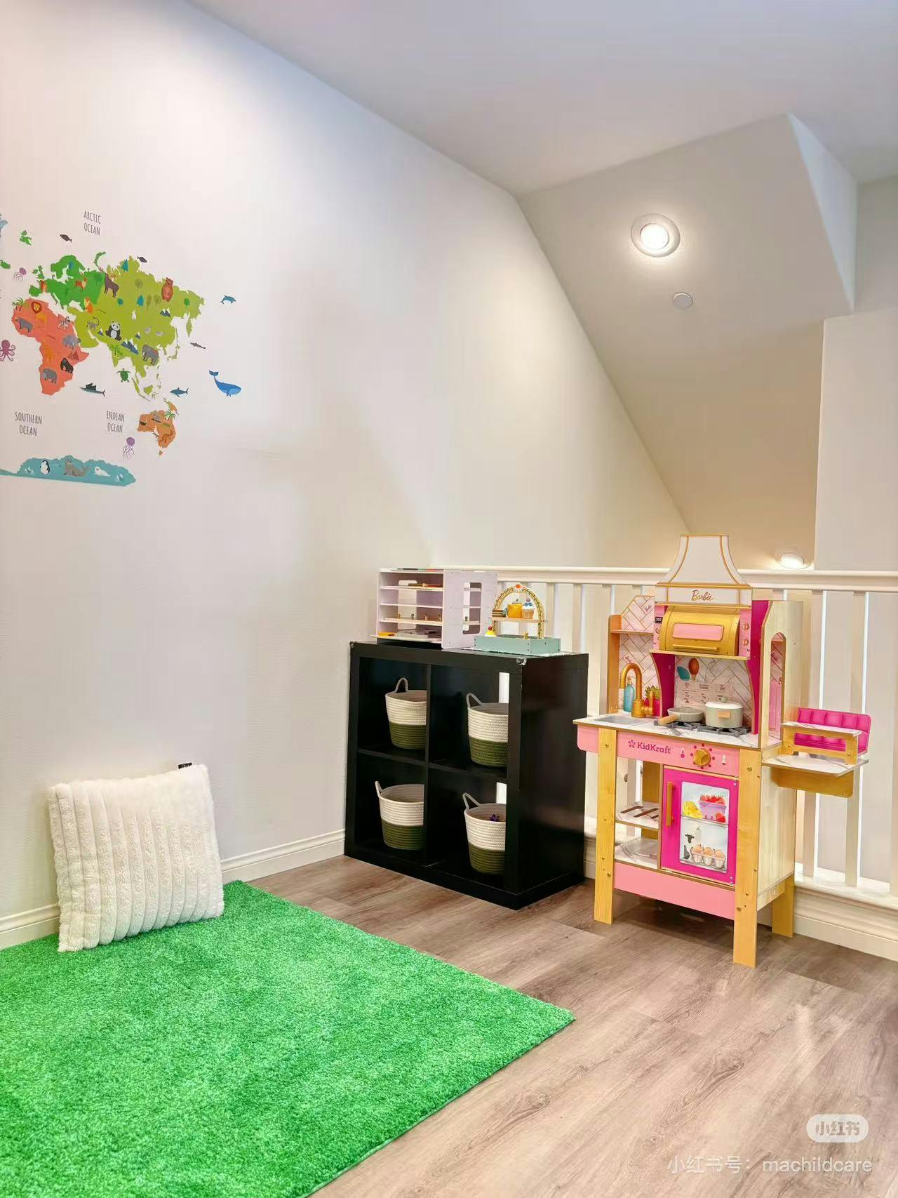 Playroom with a world map decal, green rug, toy kitchen, and storage shelf