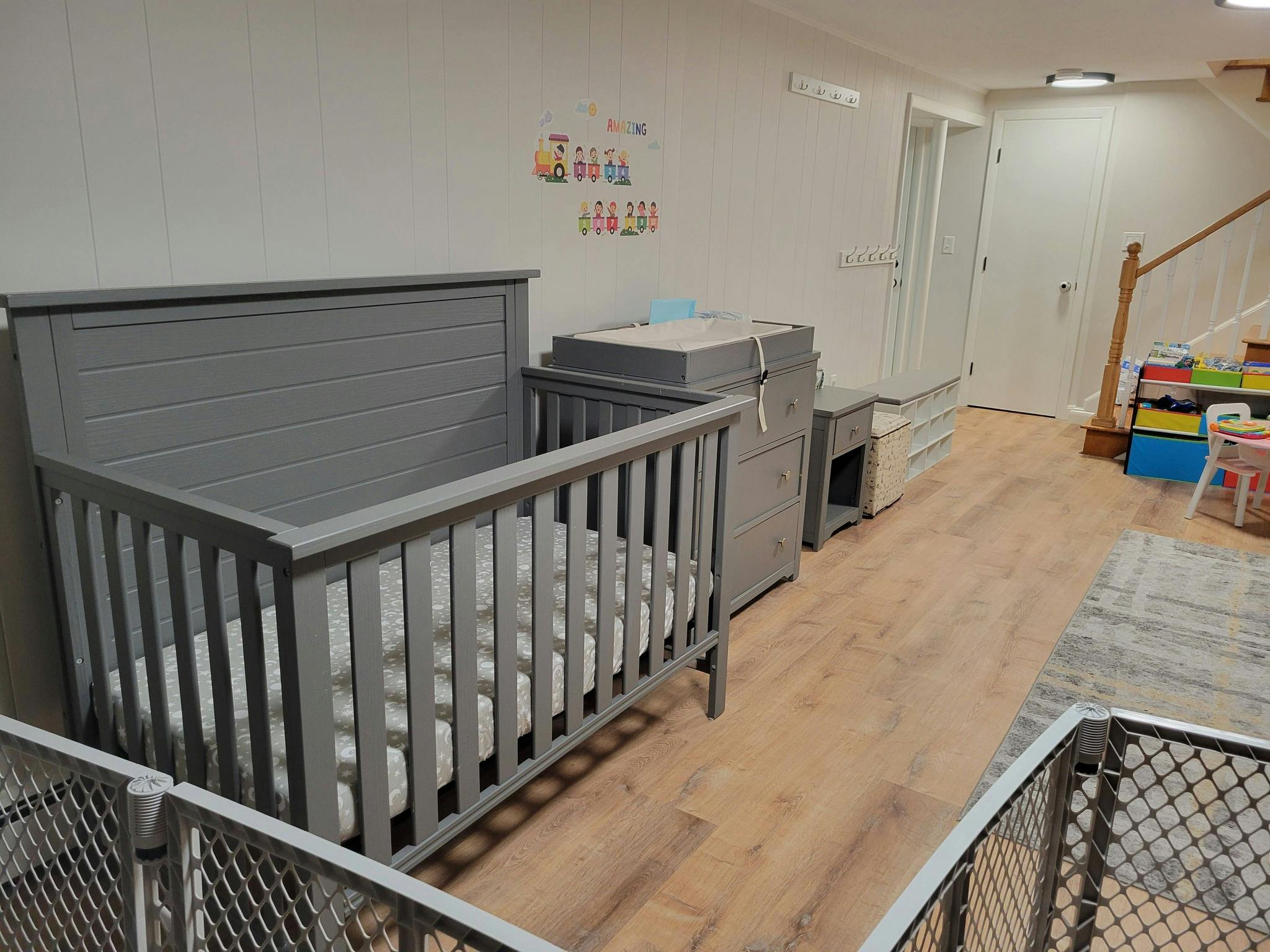 Crib and changing table in a nursery with wood floors and white walls