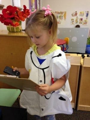 Child in doctor costume holding a clipboard and phone