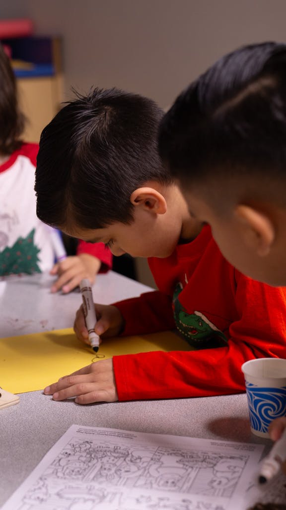 Child drawing on yellow paper with a marker