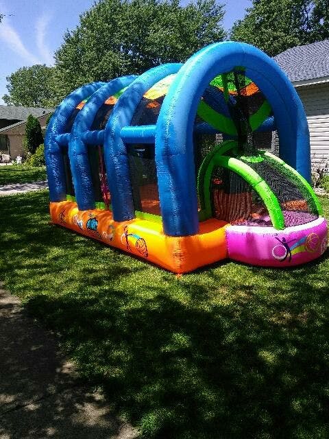 Inflatable bounce house with slide and pool on grass