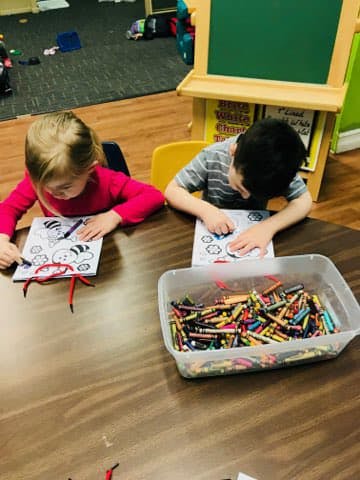 Two children coloring at a table with crayons