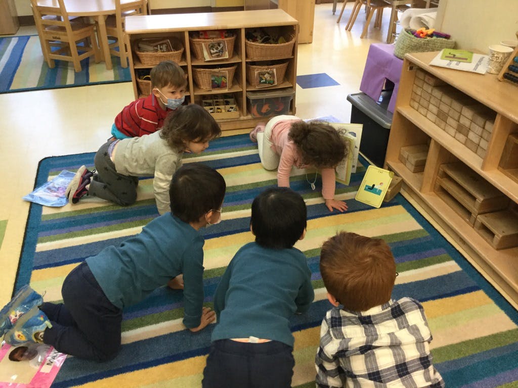 Children crawling on a striped rug in a classroom