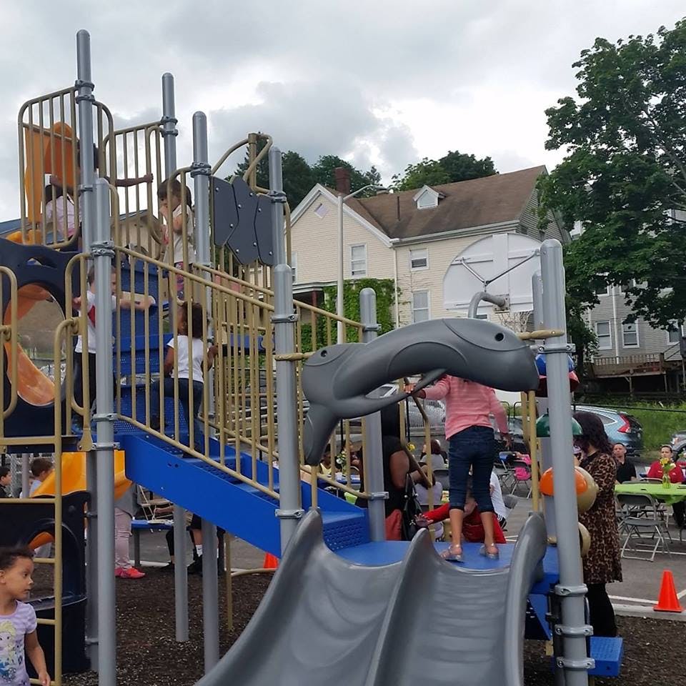 Children playing on a playground structure with slides and climbing structures
