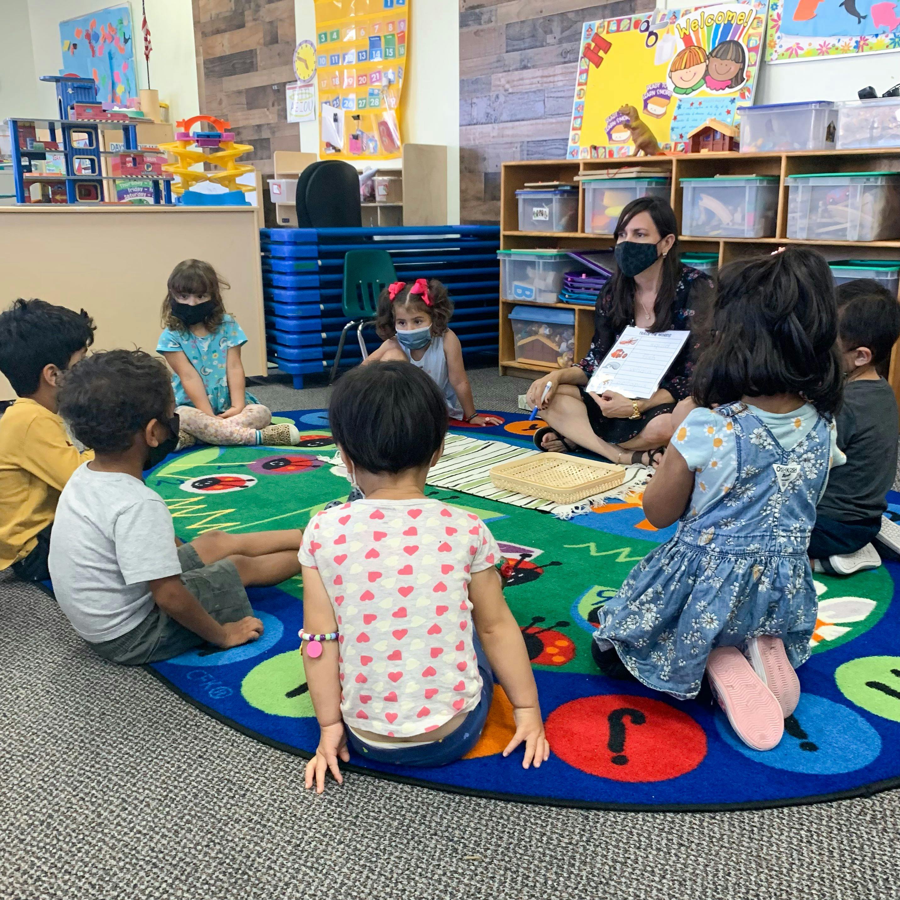 Adult and children sitting on a rug in a classroom