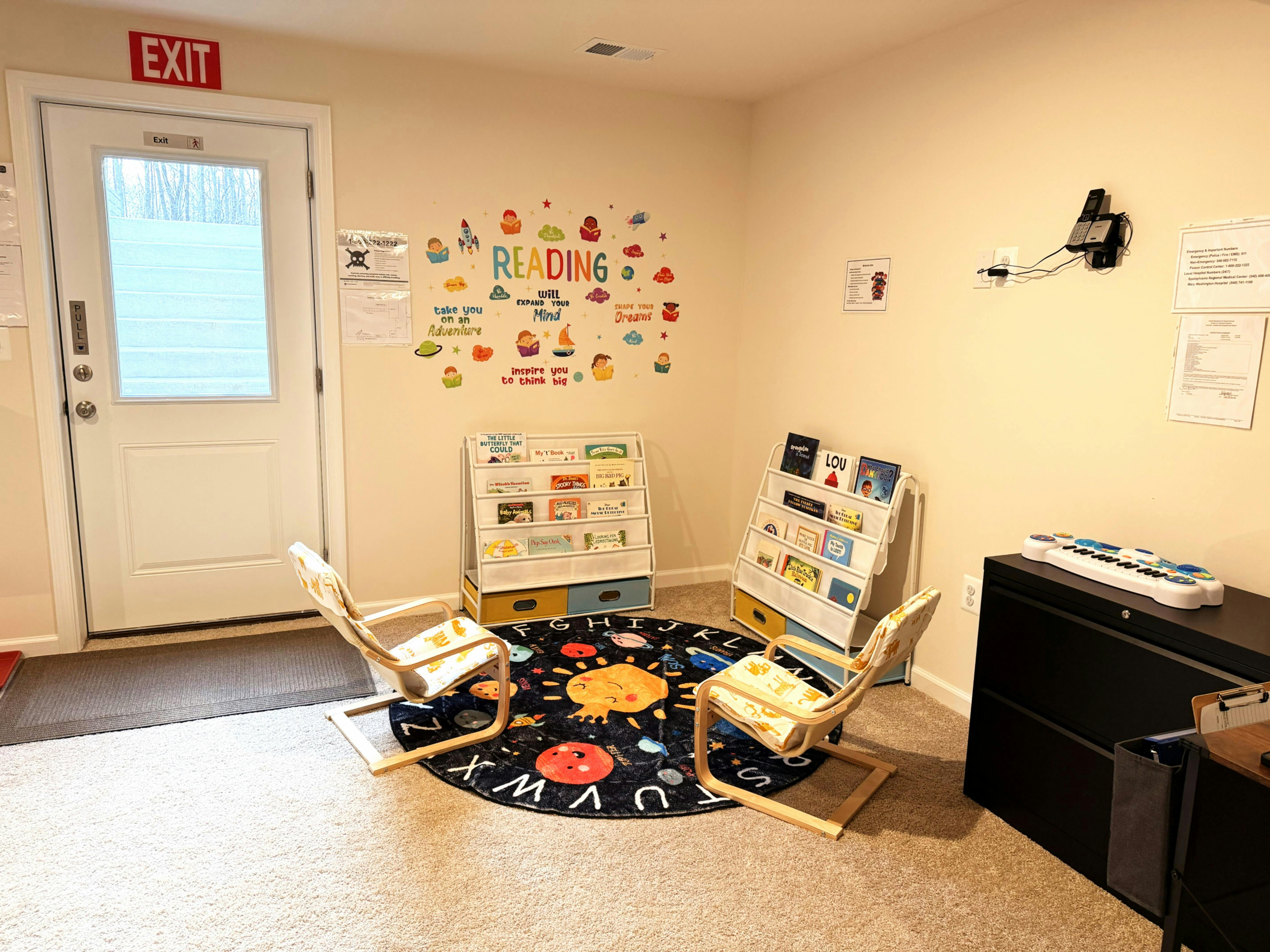 Children's reading nook with two chairs, book shelves, and a space-themed rug