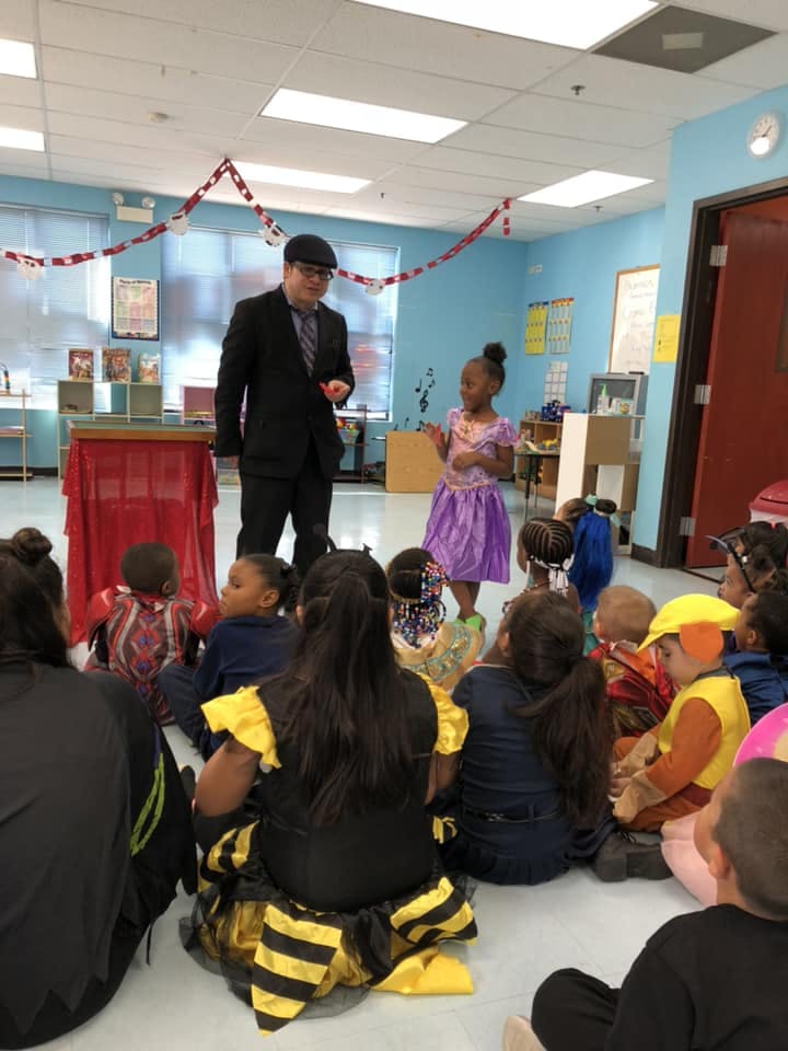 Adult and child standing in front of seated children in a classroom