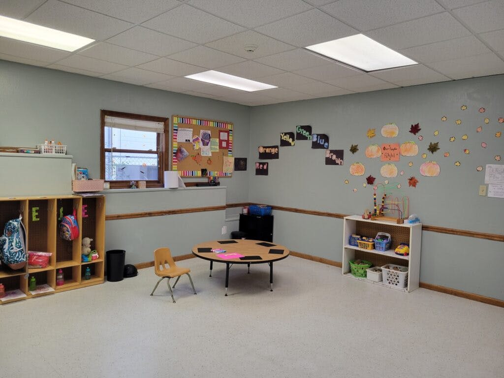 Empty classroom with small table and chairs, cubbies, and wall decorations