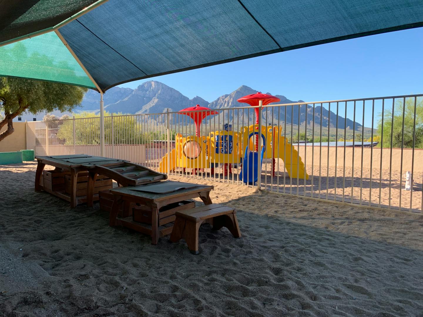 Playground with sand, climbing structure, and mountains in background