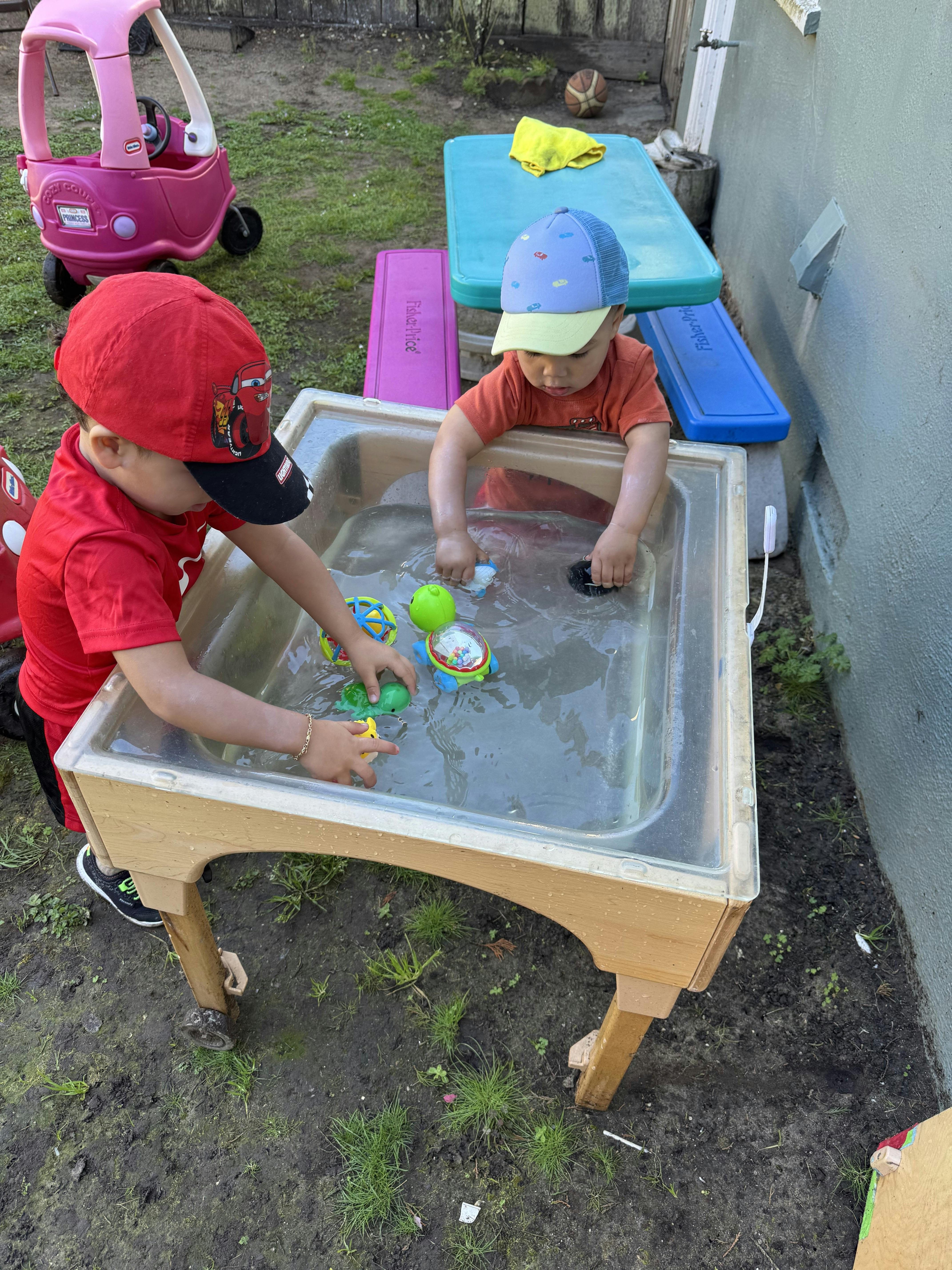 Two children playing in a water table outdoors