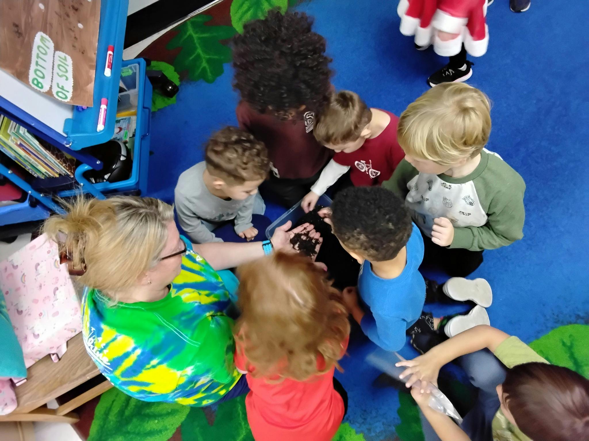 Adult and children looking at soil in a container
