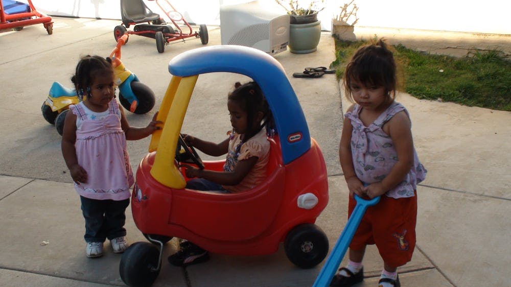 Three children playing with a toy car and a toy