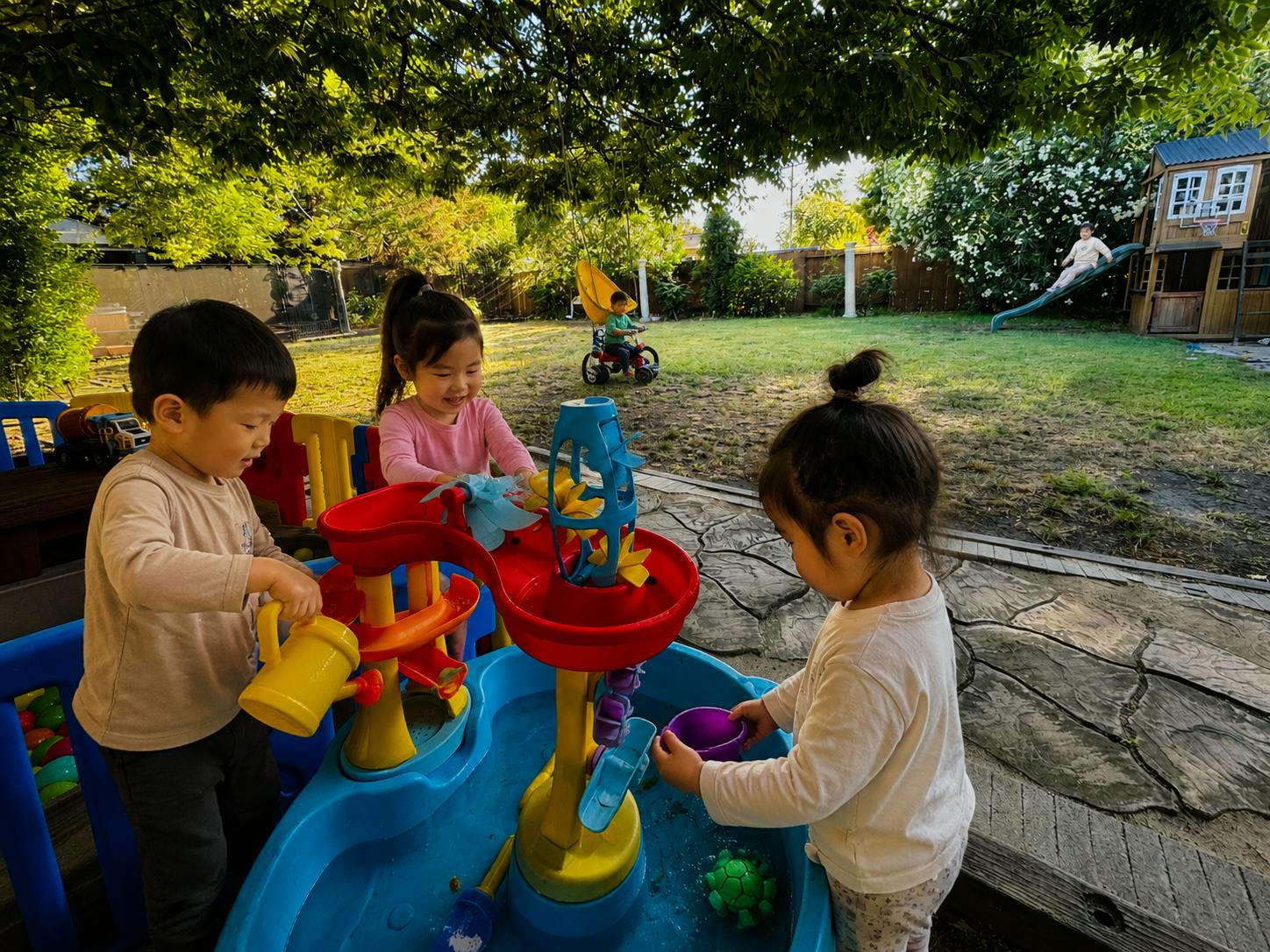 Three children playing with a water table outdoors