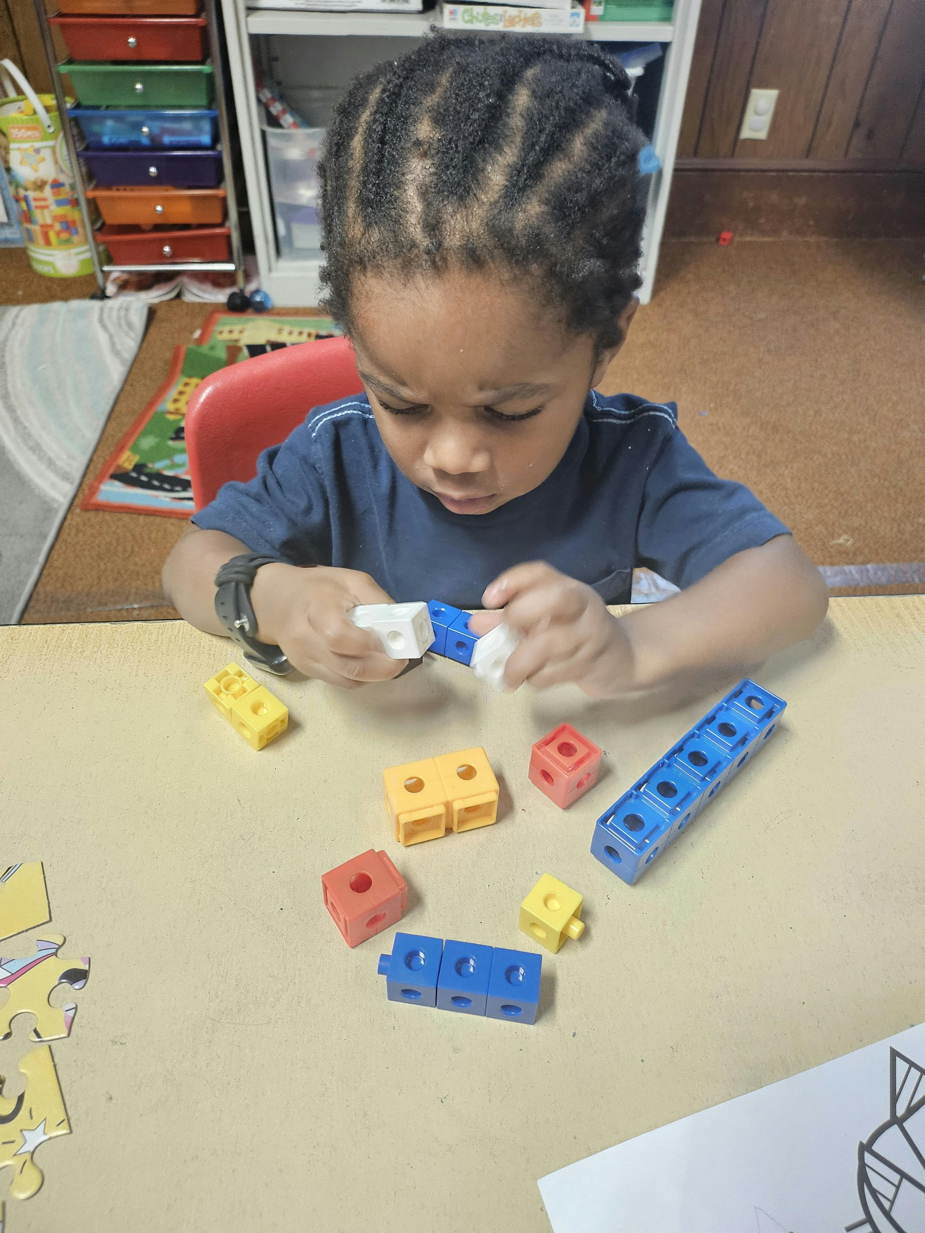 Child building with colorful plastic math cubes at a table