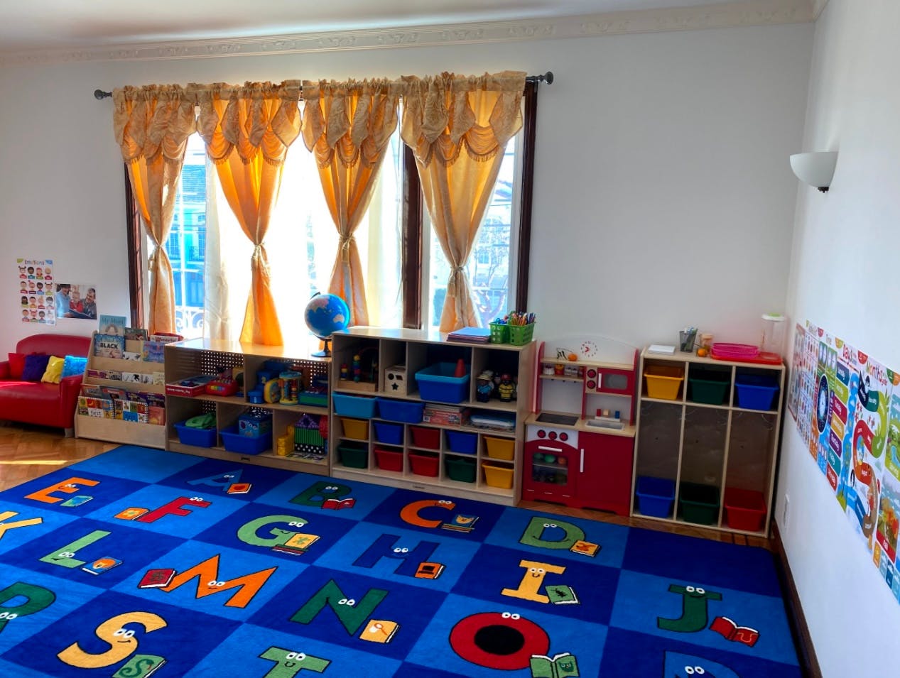 Playroom with alphabet rug, shelves of toys, and windows with windows with windows