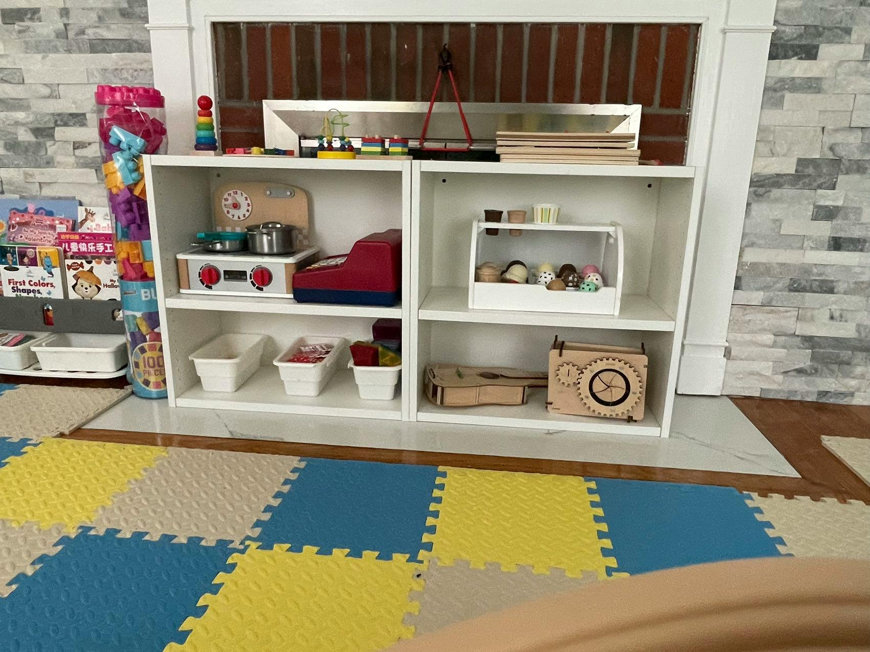 White shelving unit with toys and play kitchen items