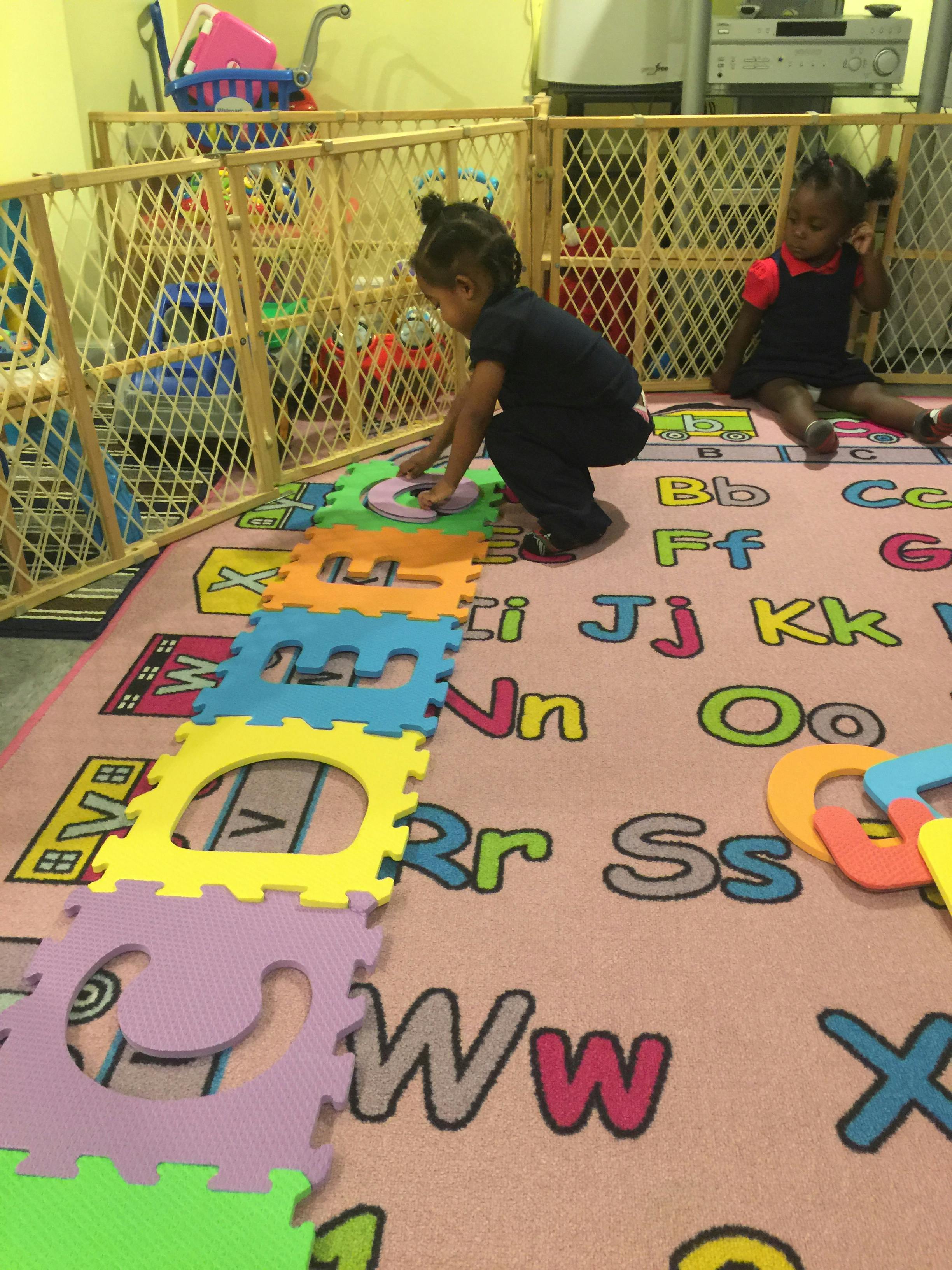 Child playing with puzzle pieces on an alphabet rug