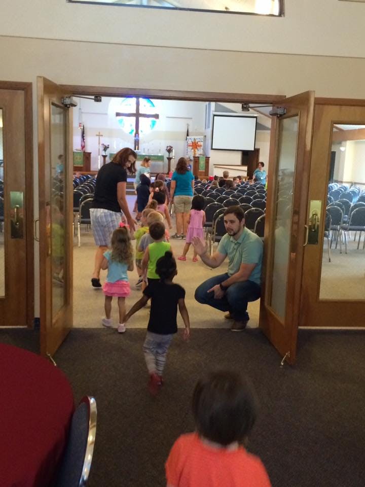 Adults and children entering a room with rows of chairs