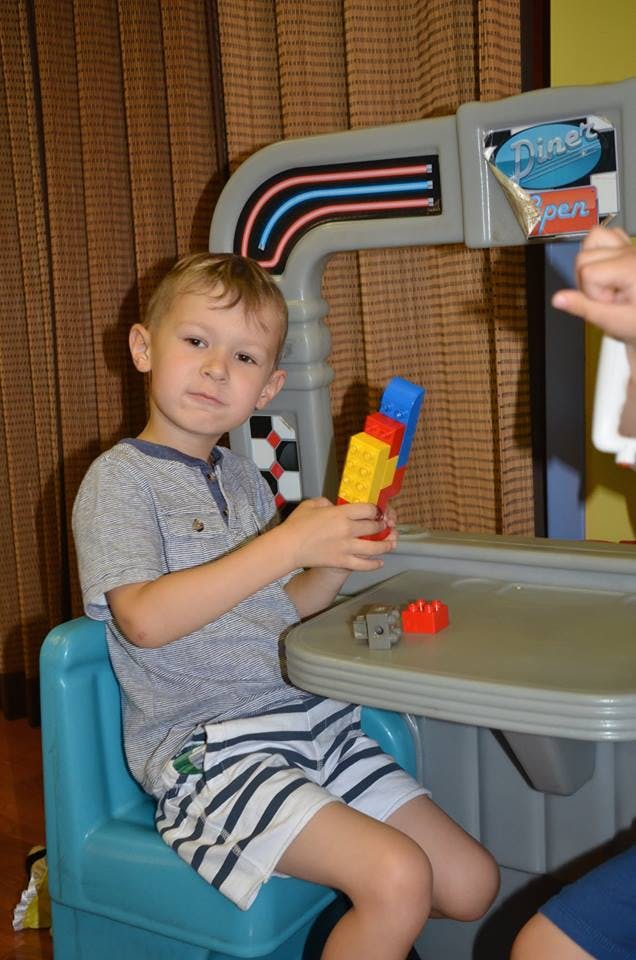Child sitting at a table holding colorful building blocks
