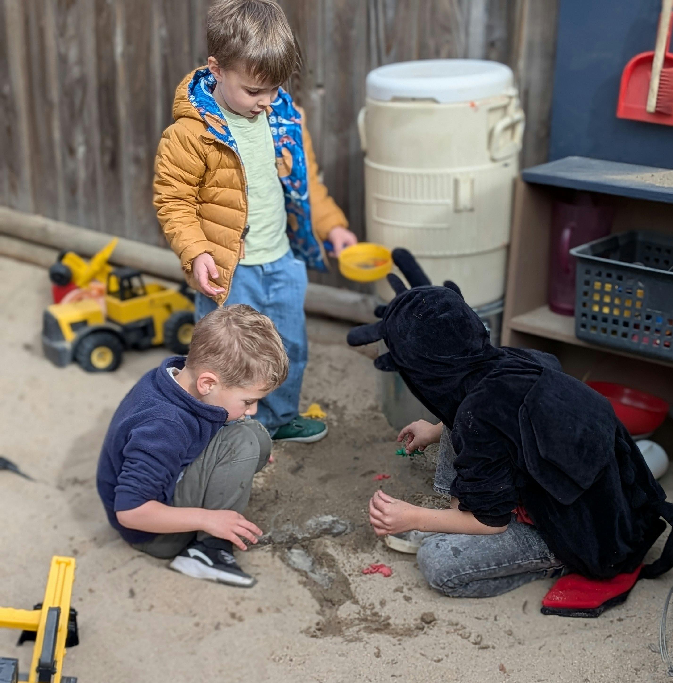 Three children playing together in a sandbox
