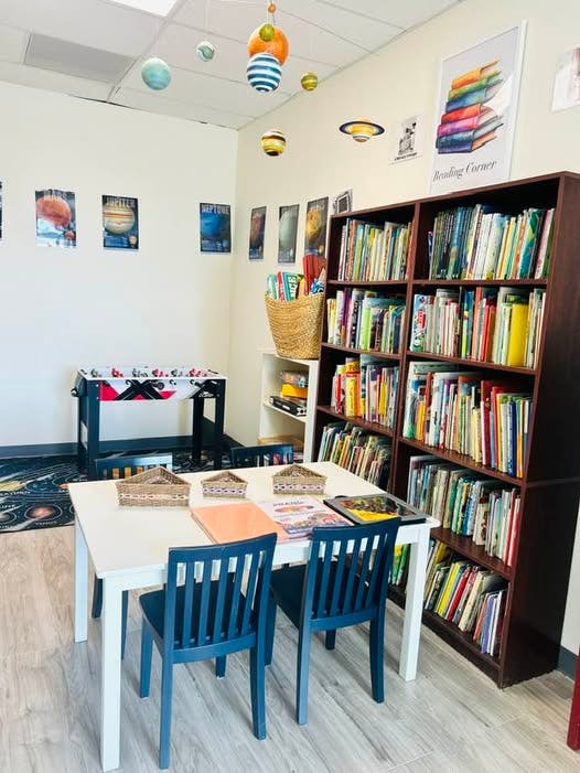 Classroom with bookshelves, a table and chairs, and planet decorations