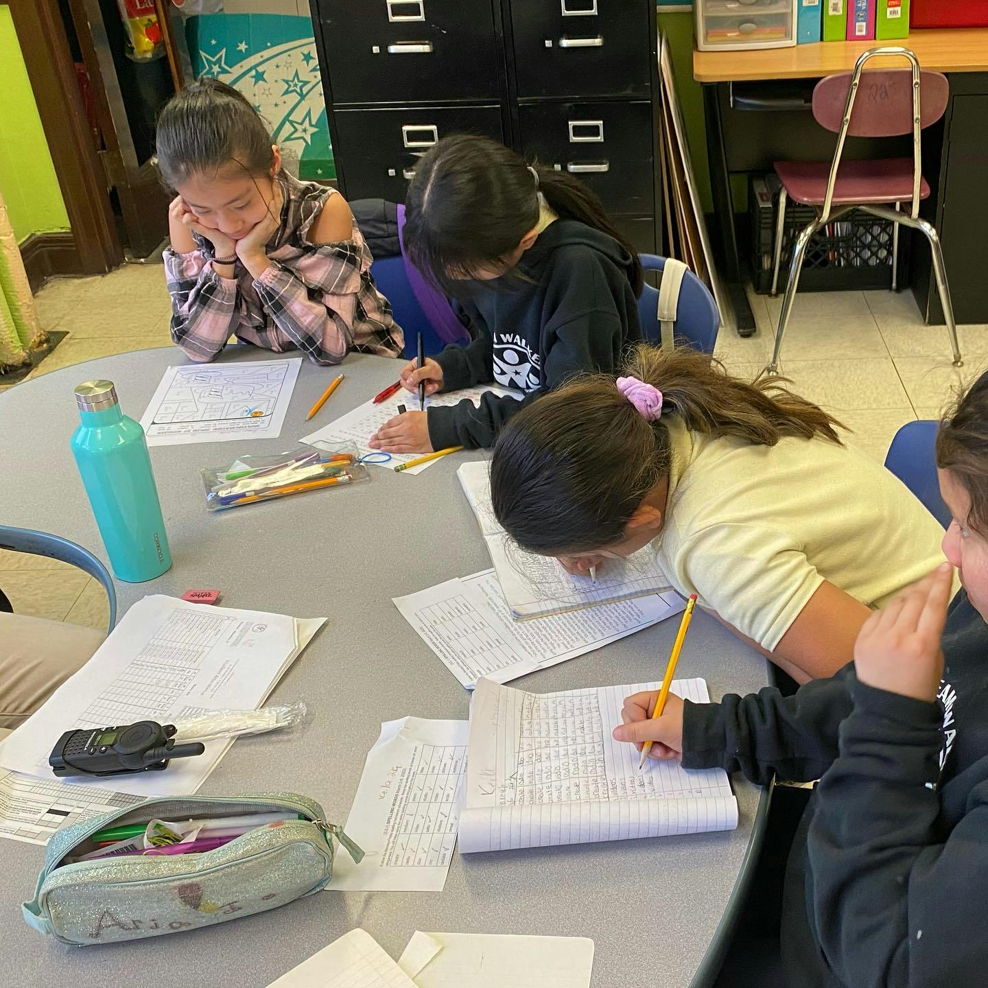 Children writing at a table in a classroom