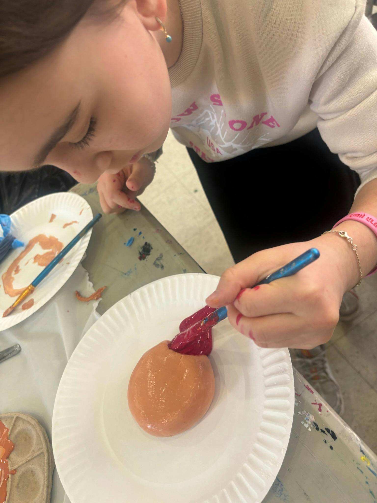 Child painting an egg on a paper plate