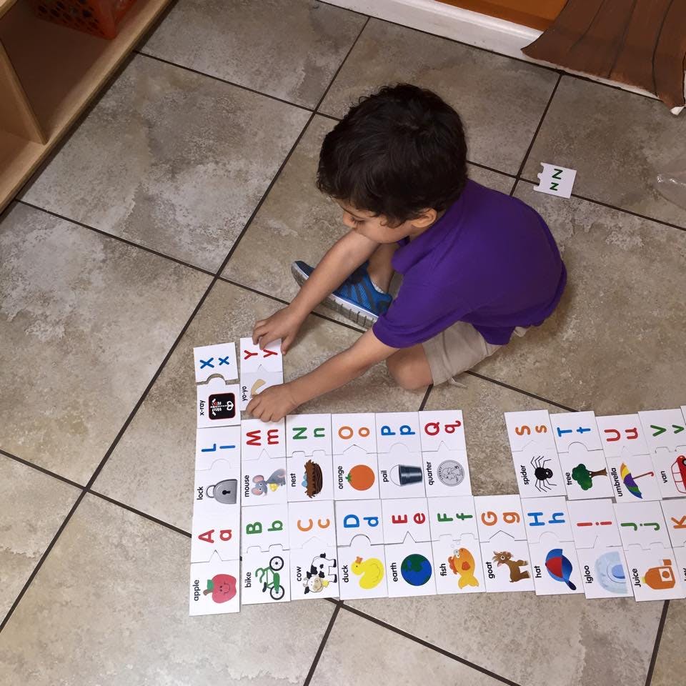 Child on floor assembling an alphabet puzzle