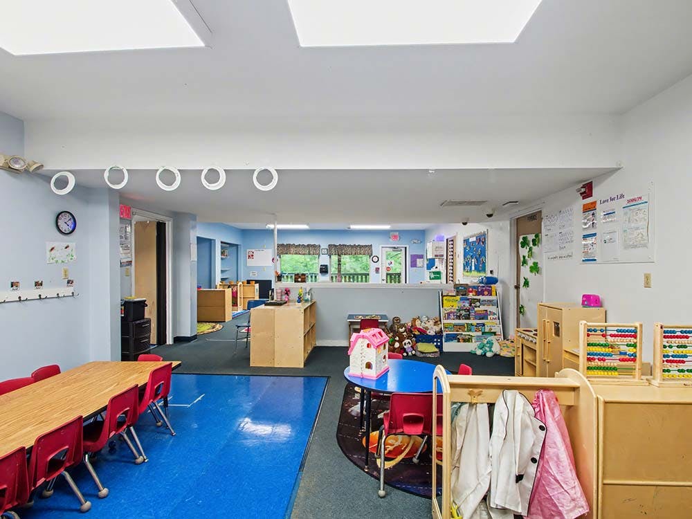 A colorful classroom with tables, chairs, and play areas