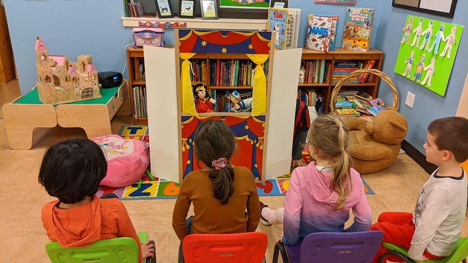 Children watching a puppet show in a classroom
