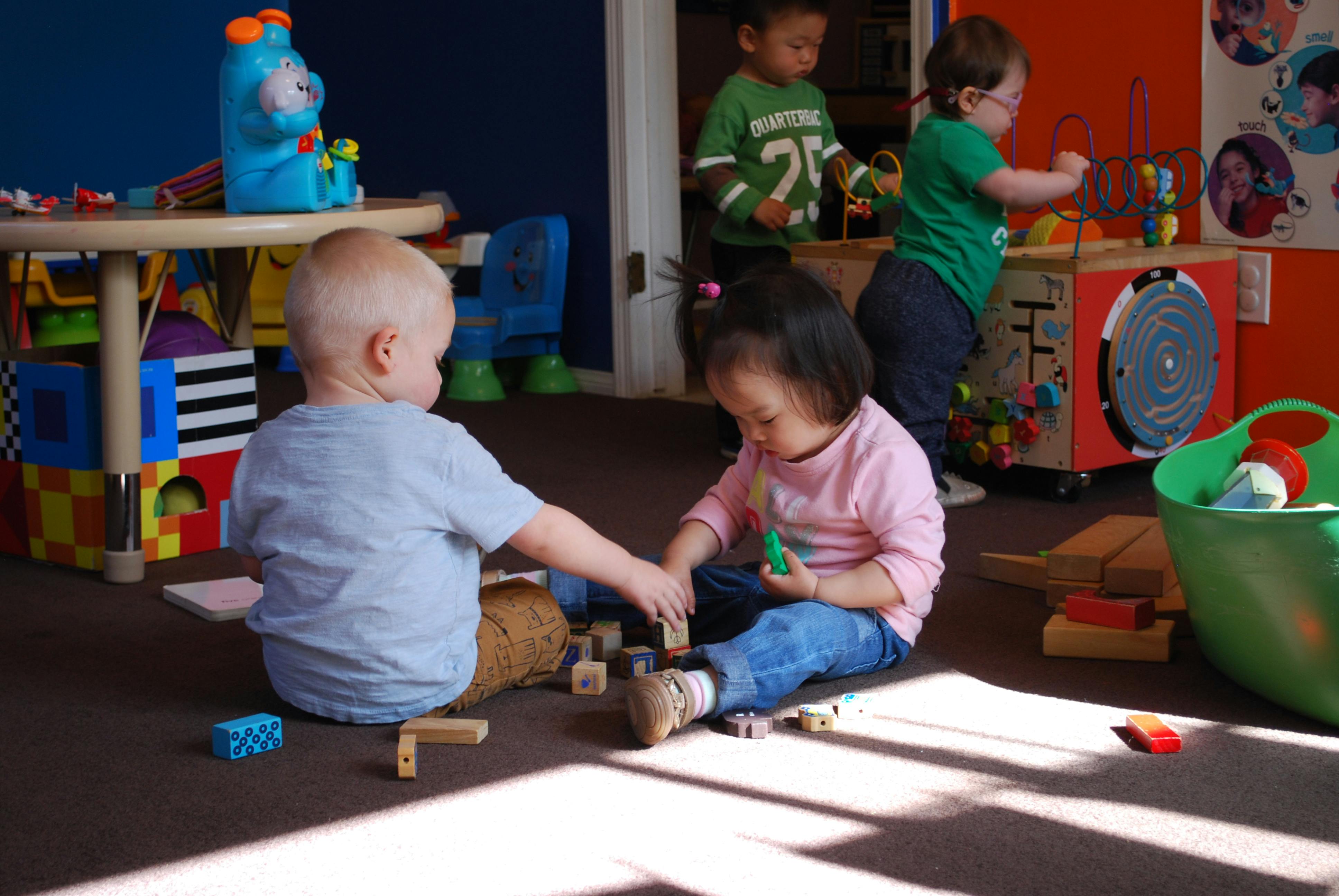 Children playing with blocks on the floor in a classroom