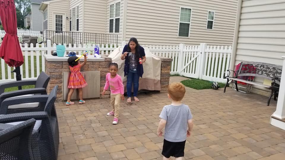 Adult and two children playing outdoors, one child running