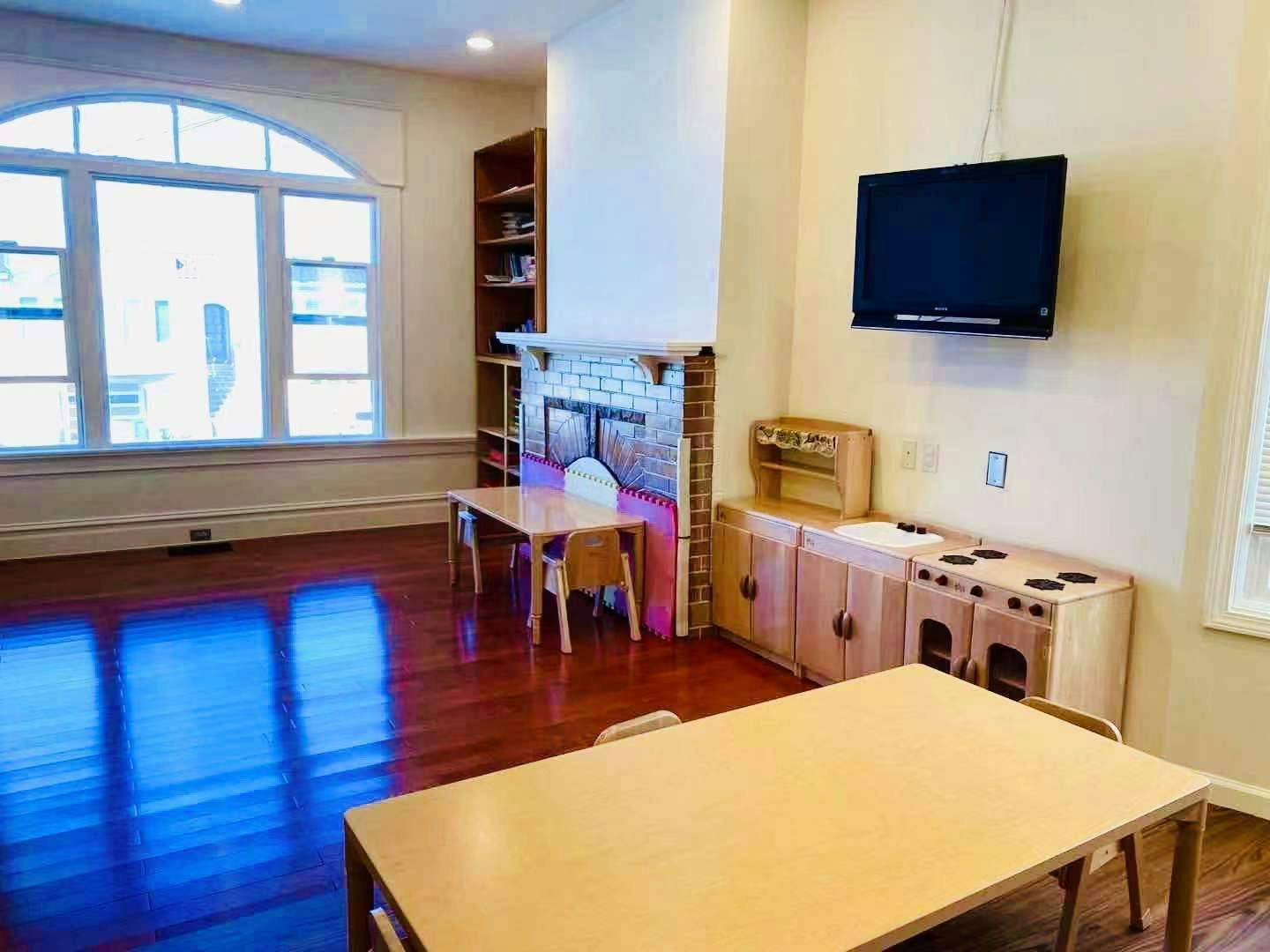 Room with small tables and chairs, a fireplace, and a play kitchen