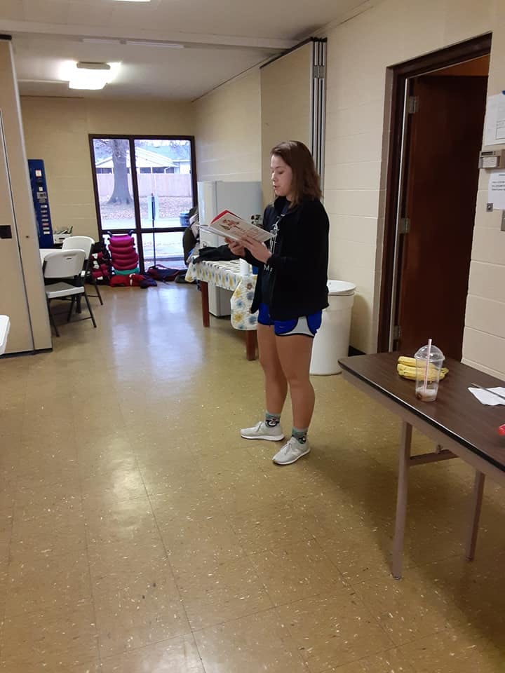 Teen standing and reading a book indoors