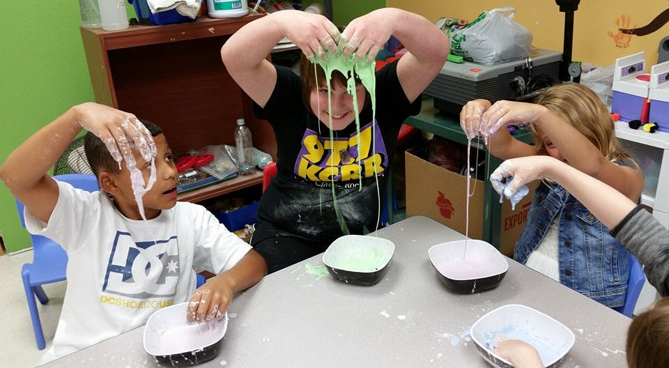 Three children playing with slime at a table
