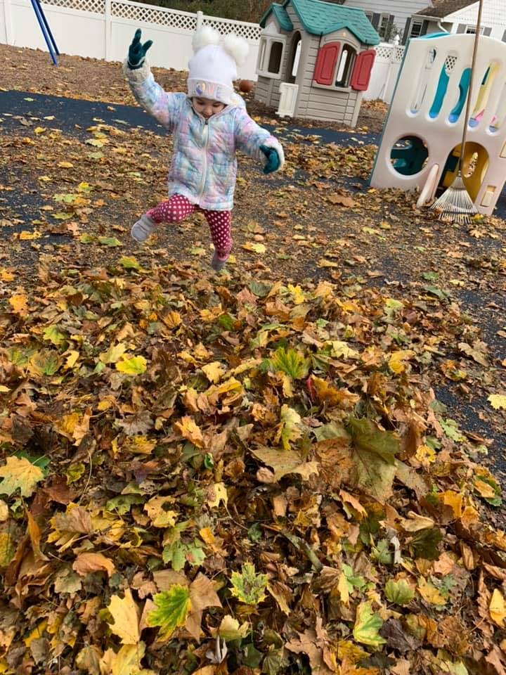 Child jumping in a pile of autumn leaves