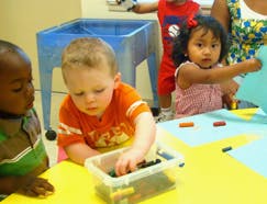 Three children playing with toys at a table