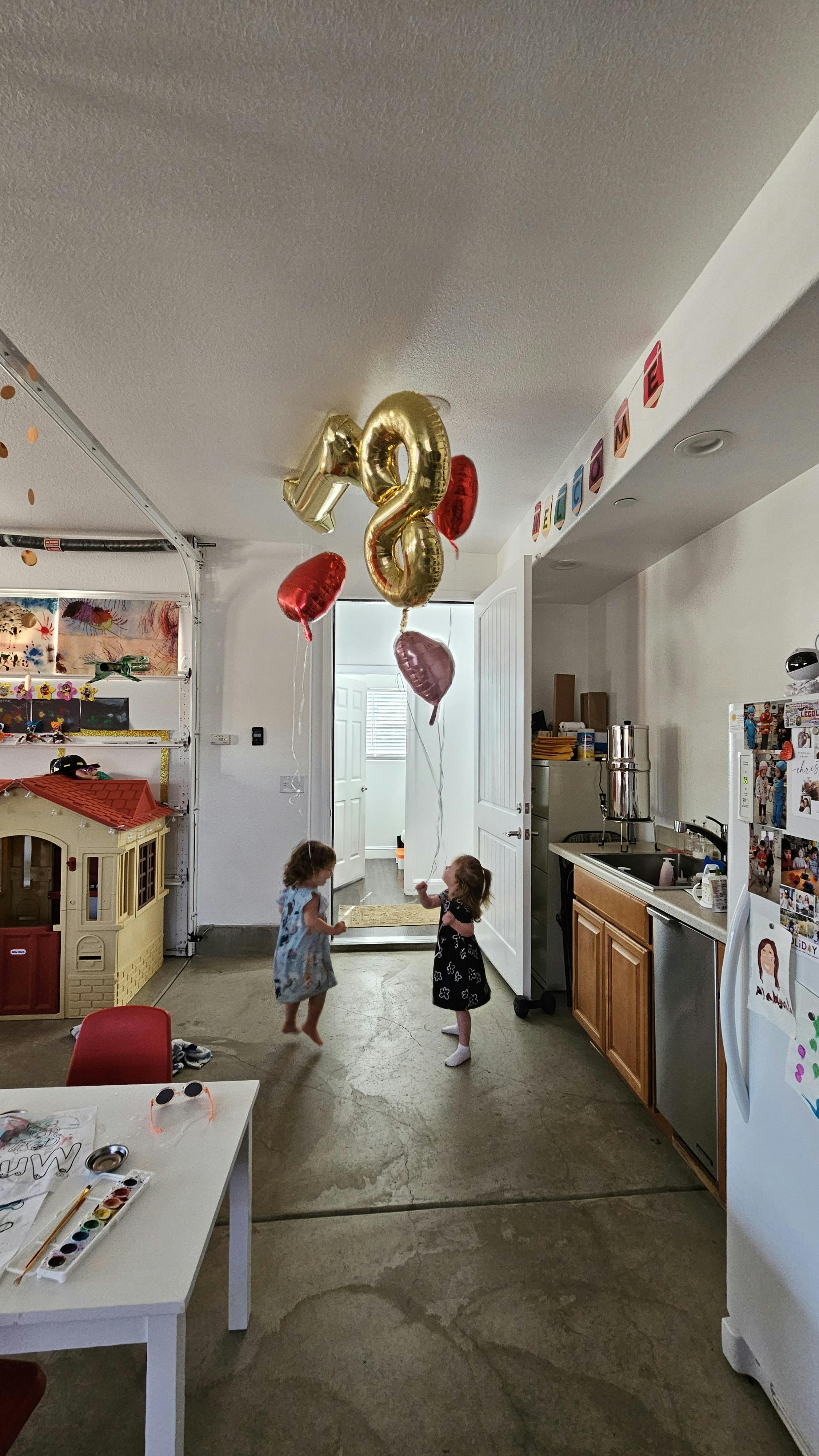 Two children looking at balloons shaped like numbers