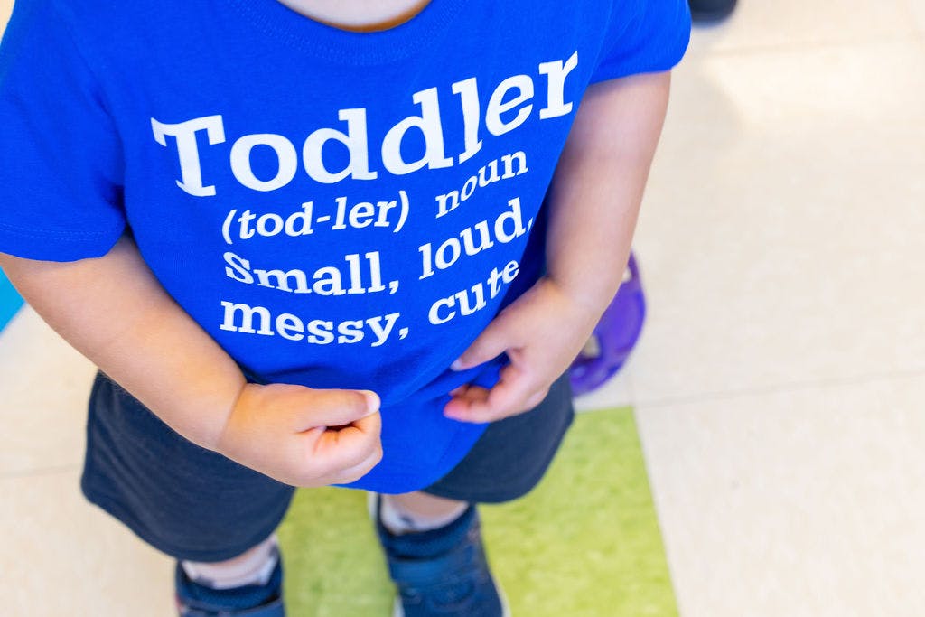 Child wearing a blue shirt with "Toddler" definition text