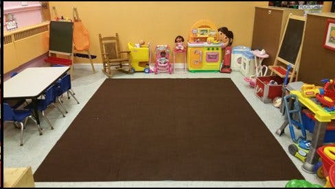 Playroom with a brown rug, small table and chairs, and various toys