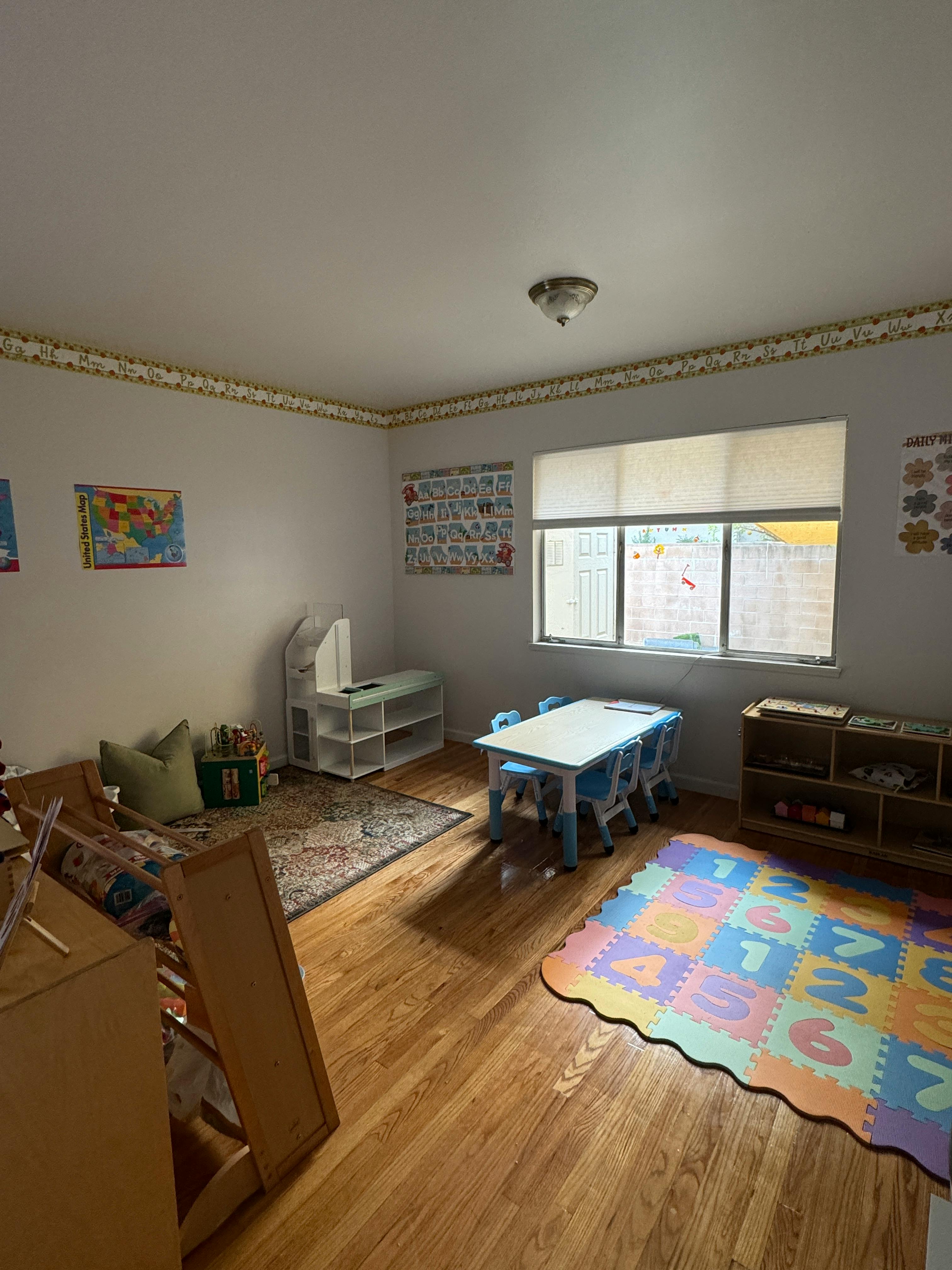 Classroom with small table and chairs, rug, and educational posters