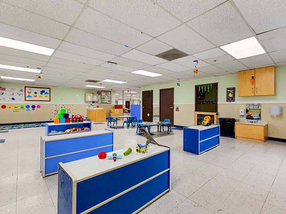 A colorful empty classroom or daycare room with small tables and toys