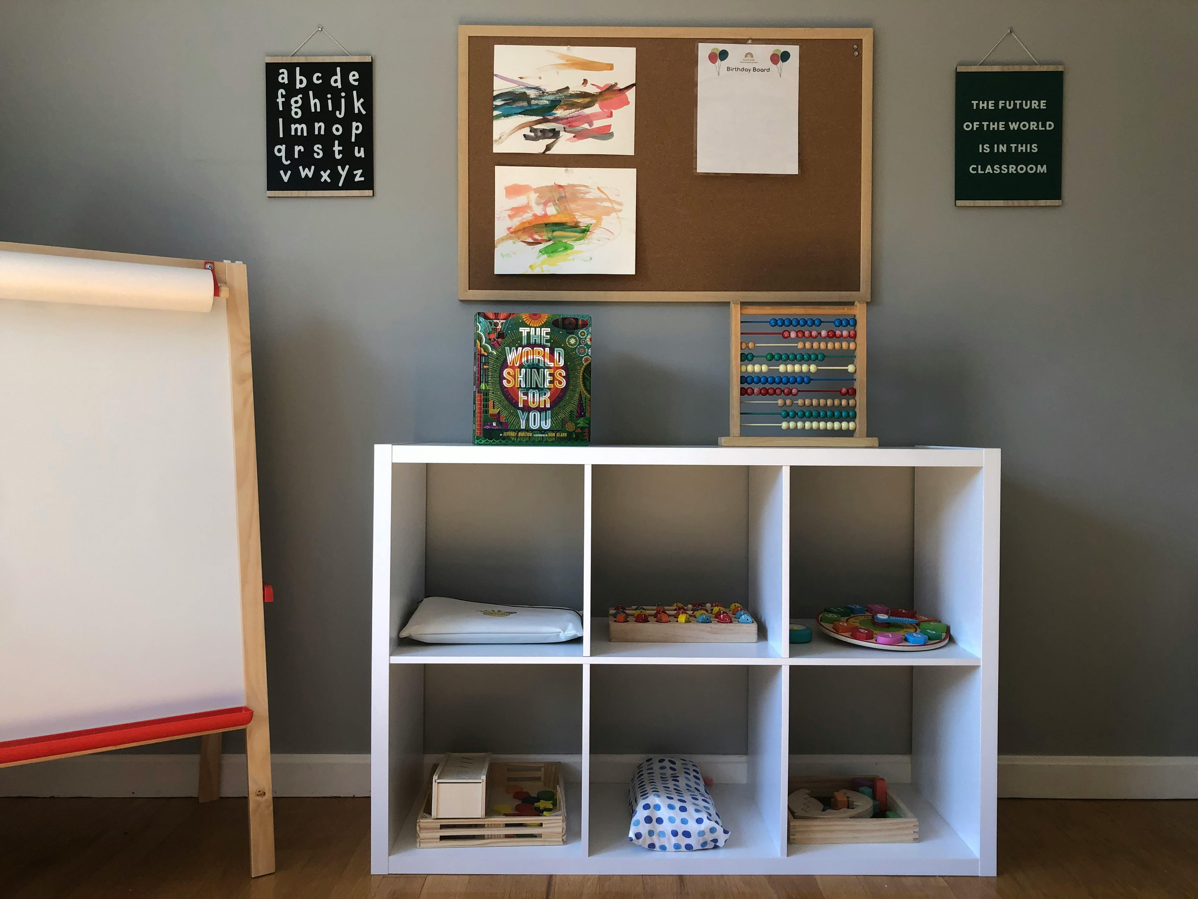 White storage cubbies with an easel, bulletin board, and abacus