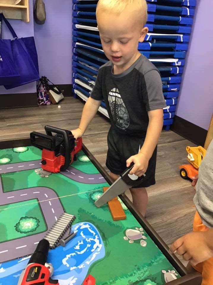 Child playing with toy tools on a playmat