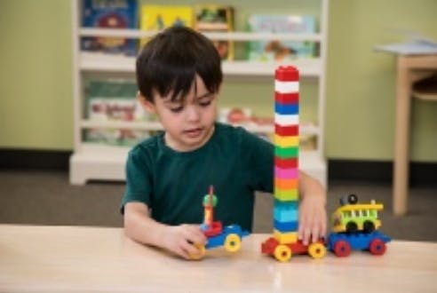 Child playing with colorful building blocks and toy cars on a table
