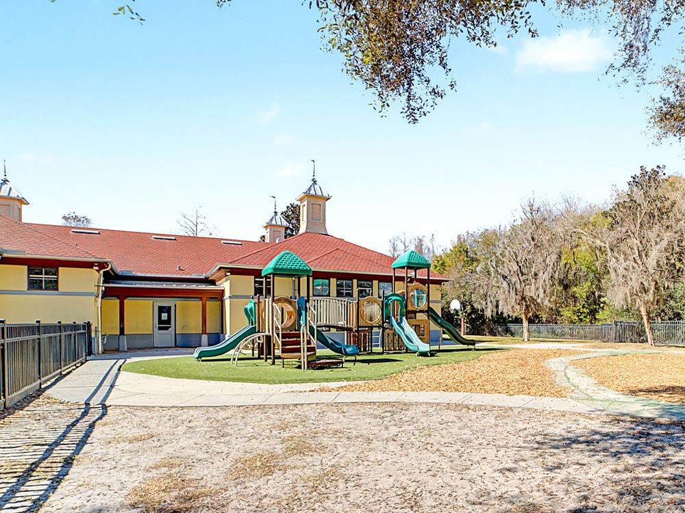 Playground equipment outside a building with a red roof