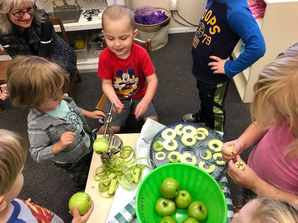 Children and adults peeling and slicing apples