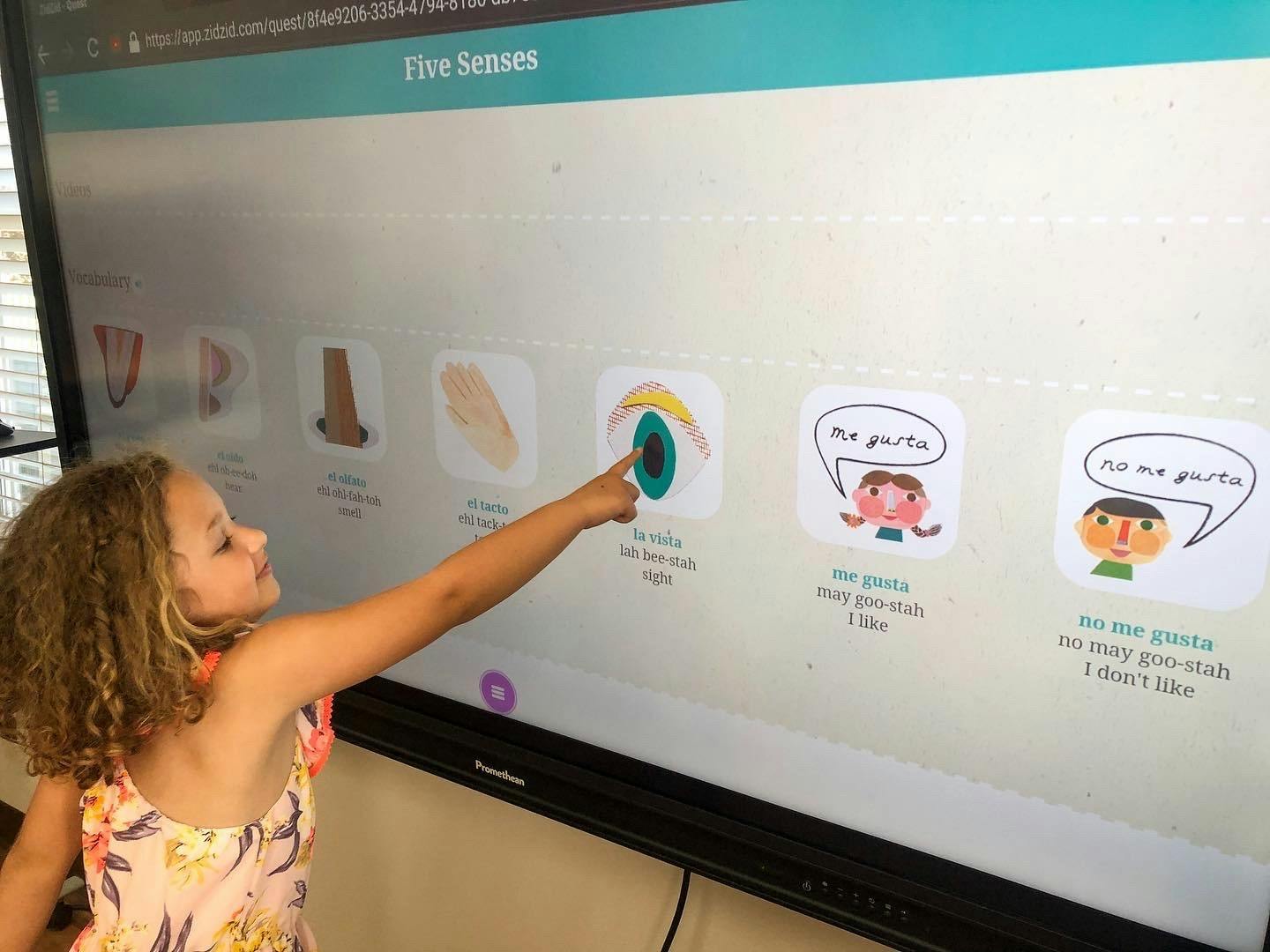 Child pointing at an interactive screen displaying "Five Senses"